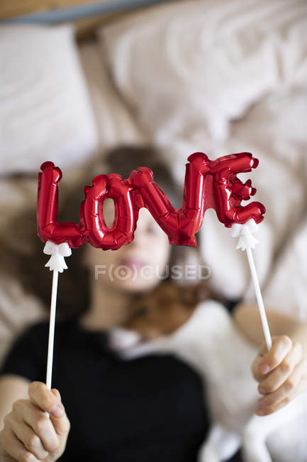 Молода жінка з собакою з червоними кульками у вигляді слова любов, вибірковий фокус — стокове фото