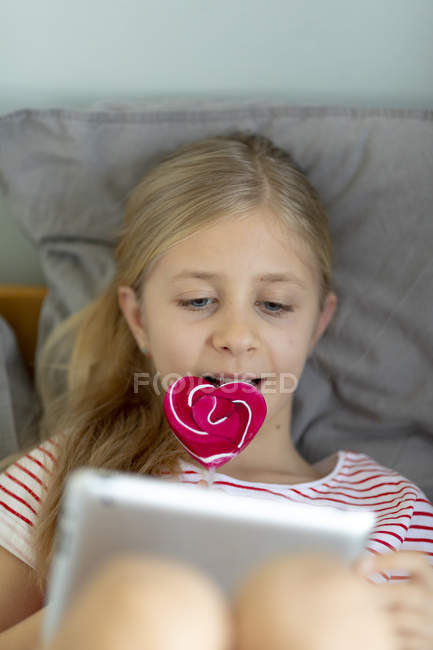 Menina bonita usando tablet digital em casa, foco em primeiro plano — Fotografia de Stock