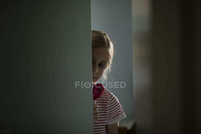 Menina comendo pirulito colorido em casa, foco seletivo — Fotografia de Stock