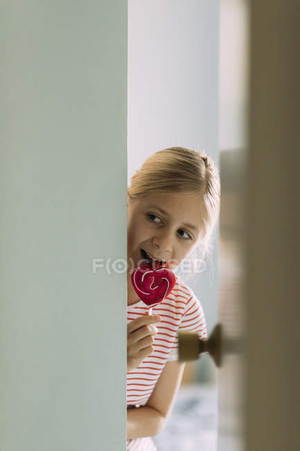 Chica comiendo piruleta dulce en casa, enfoque selectivo - foto de stock