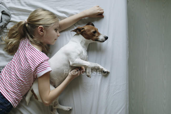 Vista elevata della ragazza con cane carino sul letto — Foto stock