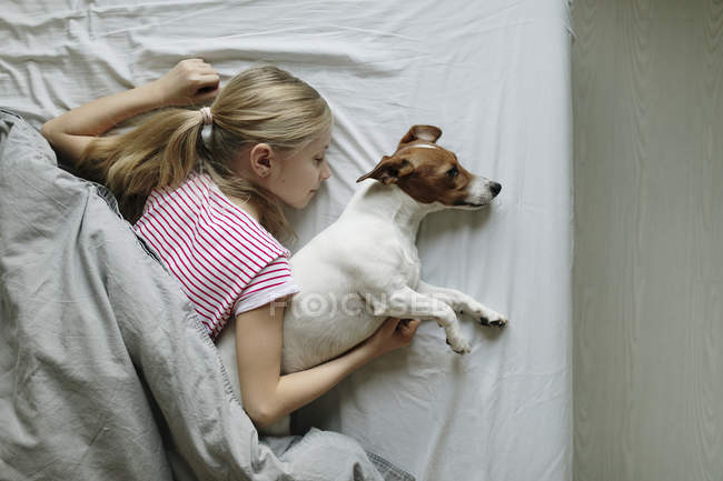 Вид девочки с симпатичной собакой на кровати — стоковое фото