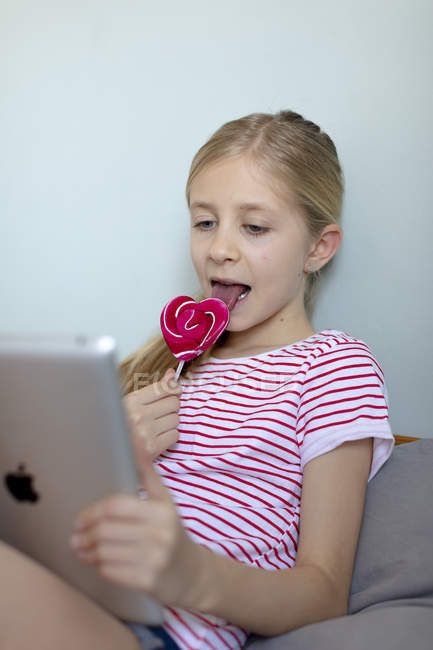 Menina bonita usando tablet digital em casa, foco em primeiro plano — Fotografia de Stock