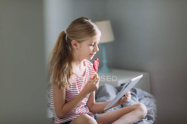 Belle fille en utilisant tablette numérique à la maison, se concentrer sur l'avant-plan — Photo de stock