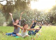 Trois enfants jetant des confettis dans l'air — Photo de stock