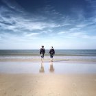 Двое детей, гуляющих на пляже — стоковое фото