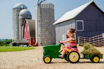 Маленькая девочка водит игрушечный трактор — стоковое фото