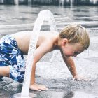 Junge spielt in Wasserfontäne — Stockfoto
