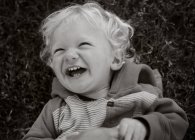 Kleinkind liegt auf Gras und lacht — Stockfoto