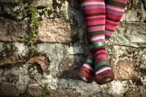 Frau in gestreiften Socken, während sie an der Wand sitzt — Stockfoto