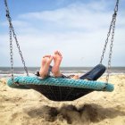 Kids lying in swing on beach — Stock Photo