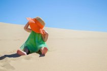 Девушка сидит на песчаном пляже — стоковое фото
