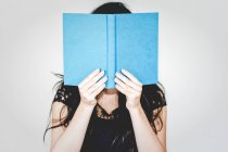 Женщина прячется за книгой — стоковое фото