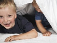 Zwei Jungen, die sich unter Bettdecke verstecken — Stockfoto