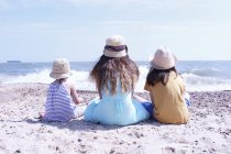 Trois filles assises sur la plage — Photo de stock