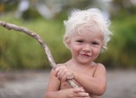 Niño en la playa jugando con palo - foto de stock