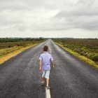 Boy walking down long road — Stock Photo