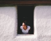Женщина выглядывает из окна — стоковое фото