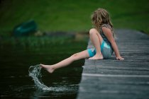 Menina sentada na doca do lago — Fotografia de Stock