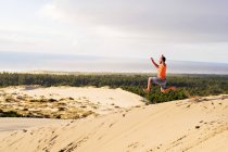 Чоловік стрибає на піщаній дюні — стокове фото