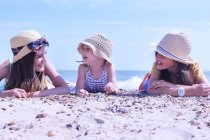 Tres chicas tumbadas en la playa - foto de stock