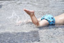 Junge planscht in Wasserfontäne — Stockfoto