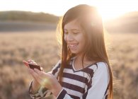 Mädchen steht auf Wiese und schreibt SMS — Stockfoto