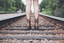 Jambes féminines debout sur les voies ferrées — Photo de stock