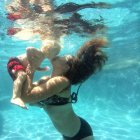 Madre baciare bambino sott'acqua — Foto stock