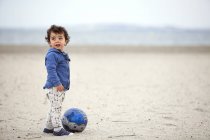 Маленька дитина на пляжі з м'ячем — стокове фото