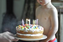 Junge pustet Kerzen auf Kuchen aus — Stockfoto
