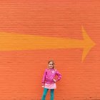 Girl standing in front of wall — Stock Photo