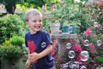 Щасливий хлопчик в саду з бульбашками — стокове фото