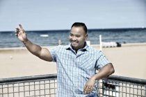 Человек машет на пляже — стоковое фото