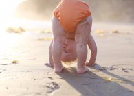 Toddler bending over on beach — Stock Photo