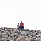 Padre e hijo sentados en las rocas - foto de stock