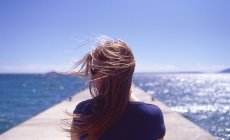 Donna con capelli che soffiano sul molo di banchina — Foto stock
