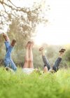 Children lying on lawn and rising legs up — Stock Photo
