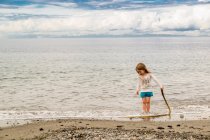 Petite fille debout sur la plage — Photo de stock