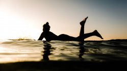 Силуэт женщины на доске для серфинга — стоковое фото