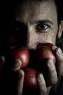 Homem está segurando maçãs na frente da cara — Fotografia de Stock