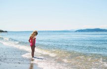 Cute girl standing by sea — Stock Photo