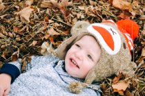Мальчик лежит в куче листьев — стоковое фото