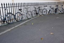 Bikes parked along fence — Stock Photo
