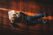 Хлопчик лежить на підлозі, малює картину — стокове фото