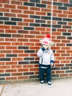 Хлопчик спирається на цегляну стіну — стокове фото