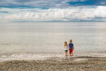 Девочка и мальчик, стоящие на пляже — стоковое фото