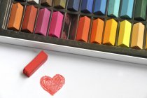 Multi colored chalks and red heart — Stock Photo