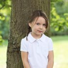 Menina em pé junto à árvore — Fotografia de Stock