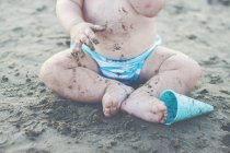 Niño sentado en la arena de la playa - foto de stock